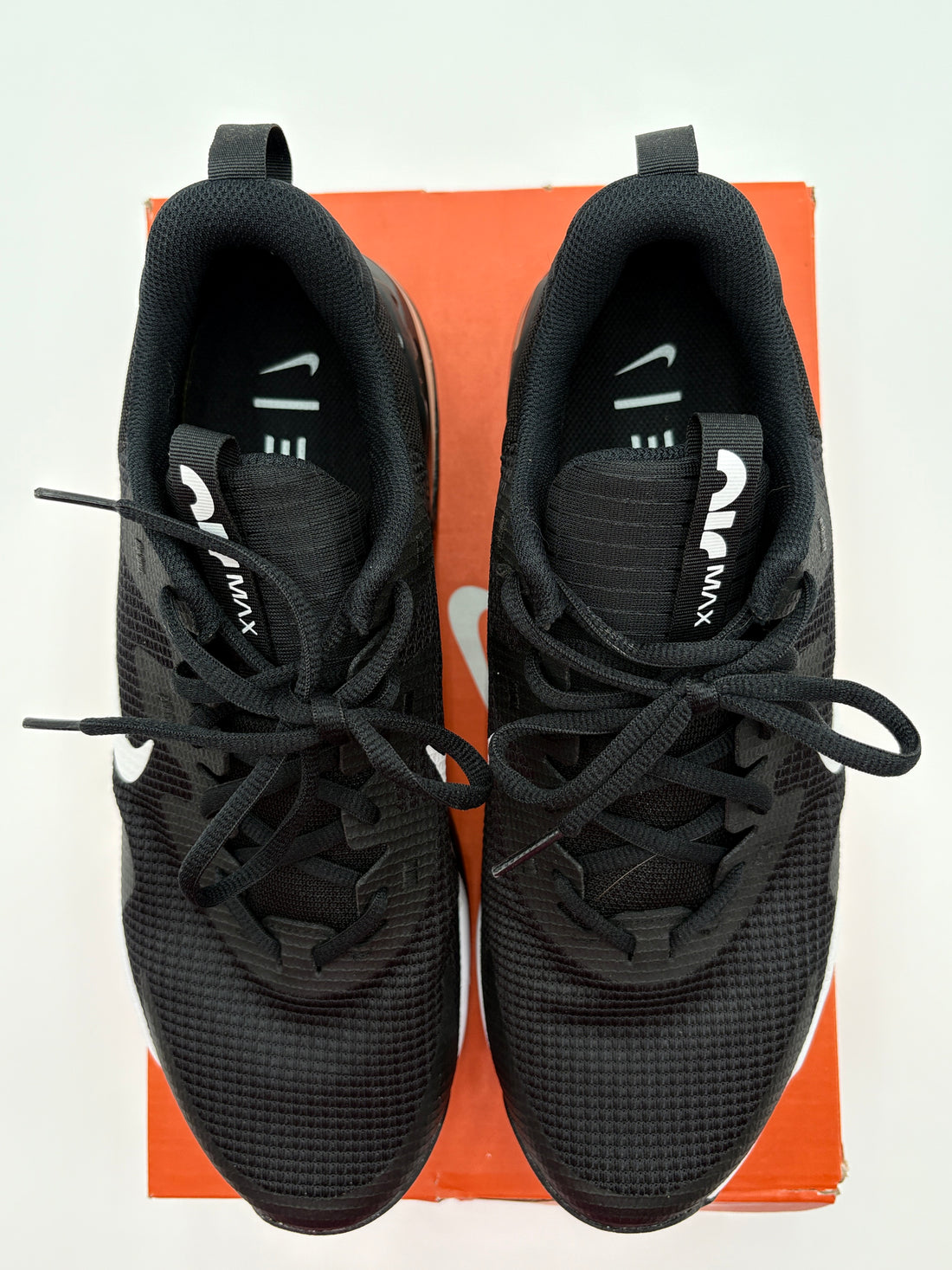 Black Nike sneakers on a brown shoe box with a white background