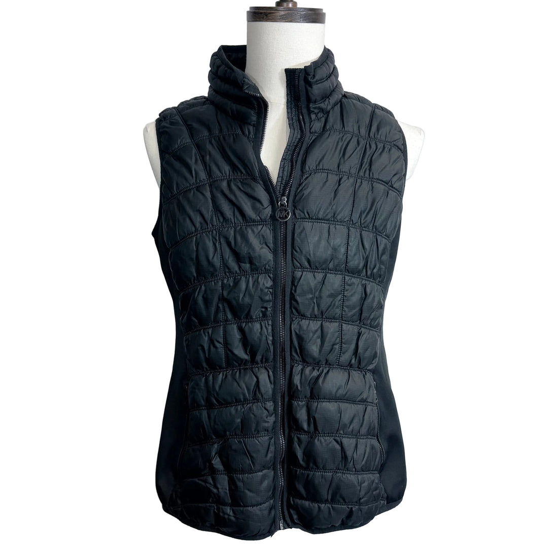 Woman wearing a black puffer vest on a beach at sunset with 'UrbanRevivalFashion.com' branding.