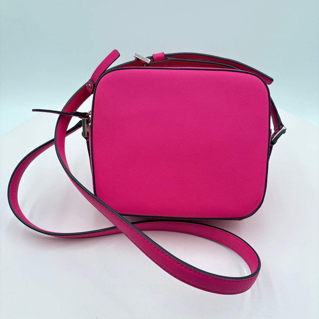 Pink handbag with a matching strap on a light gray background