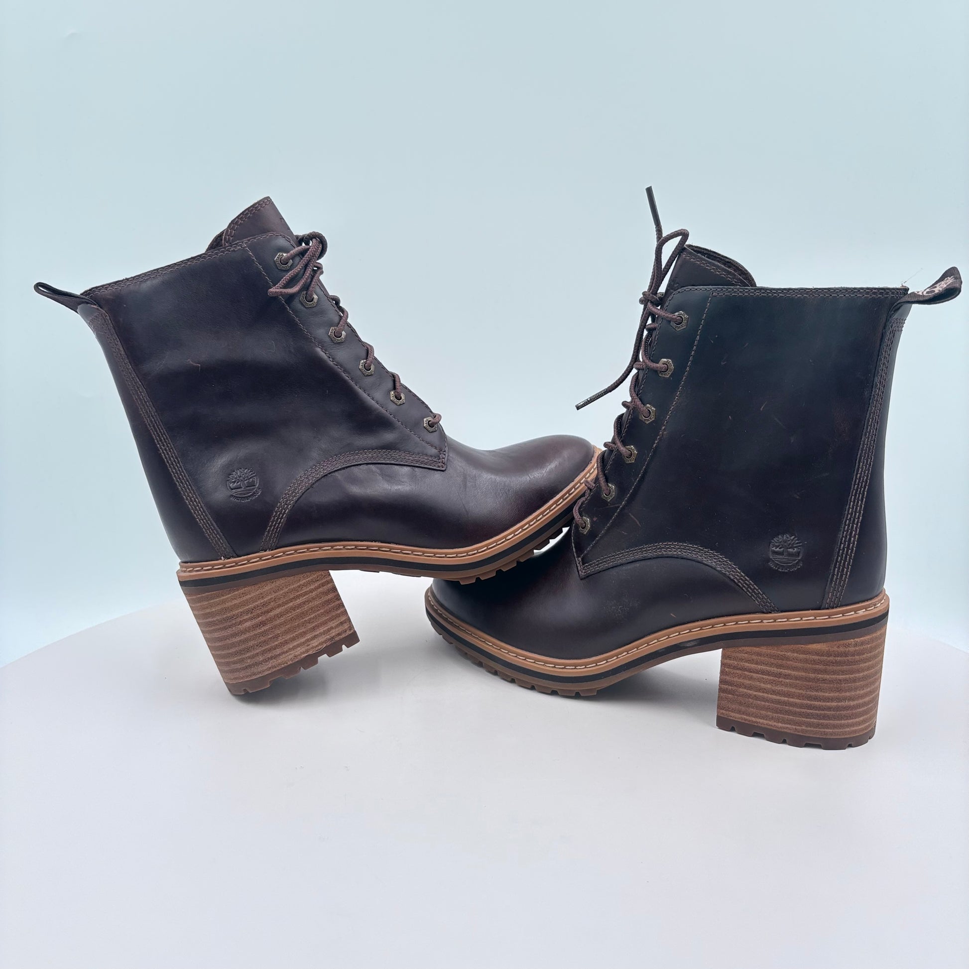 Pair of dark brown leather boots with wooden soles on a light gray background