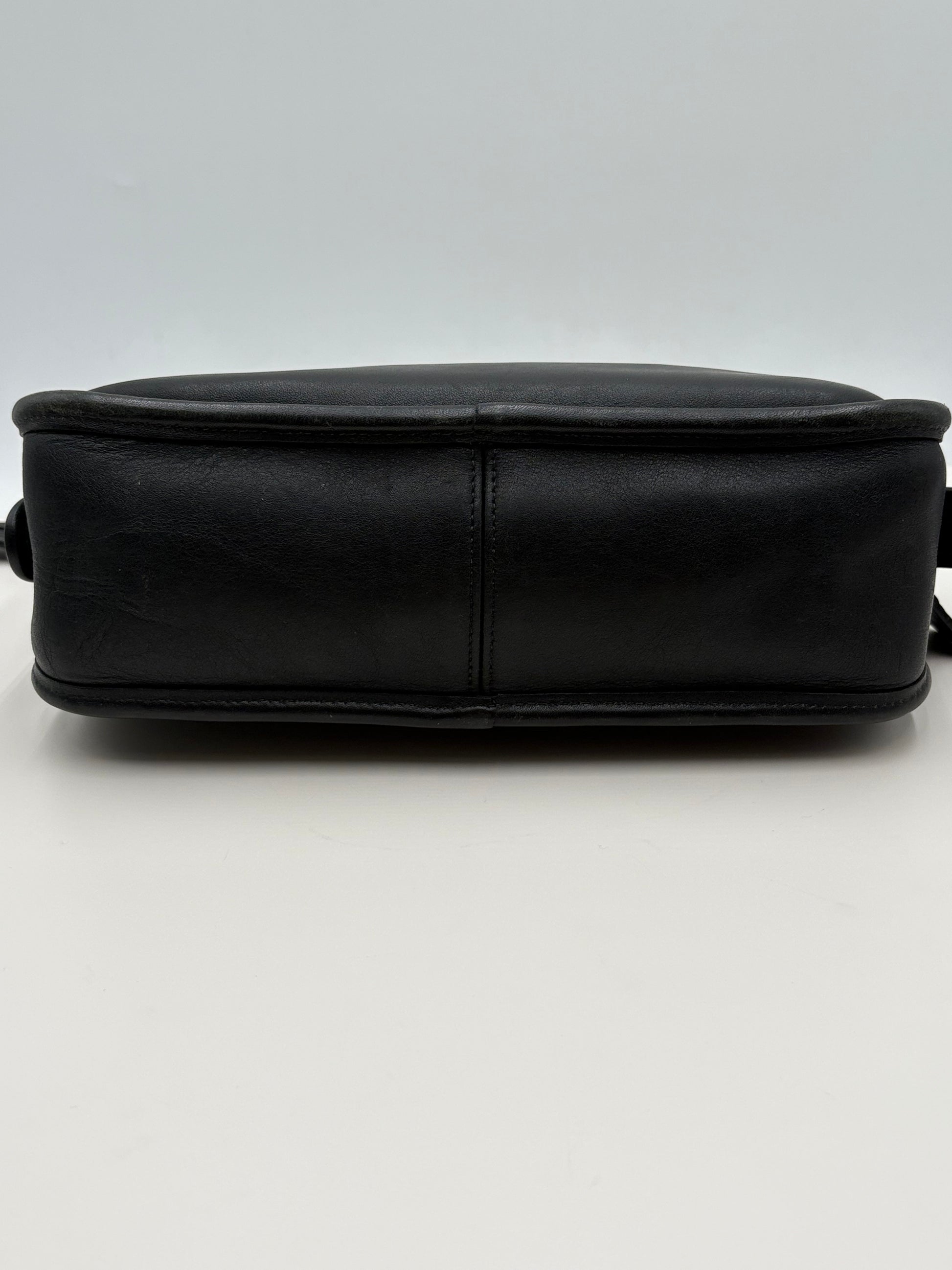 Black leather vintage coach bag on a light gray background