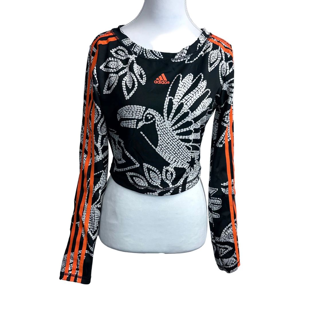 Black long-sleeve top with white and orange patterns on a mannequin against a gray background