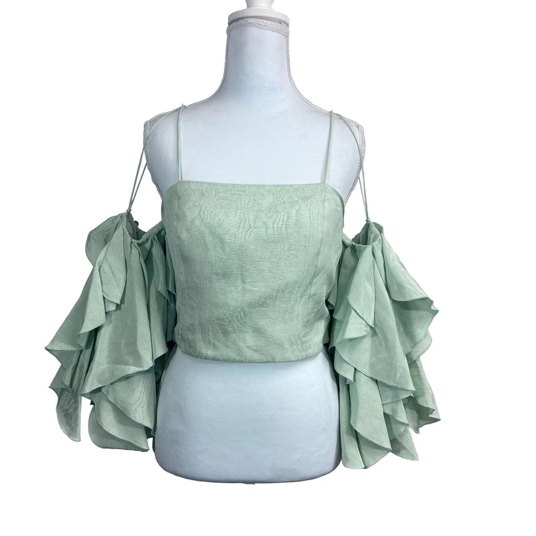 Light green top with ruffled sleeves on a mannequin against a white background
