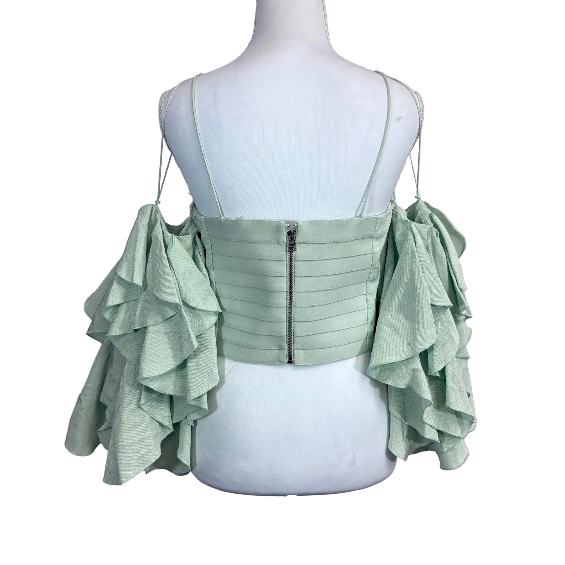 Light green ruffled top on a mannequin against a white background