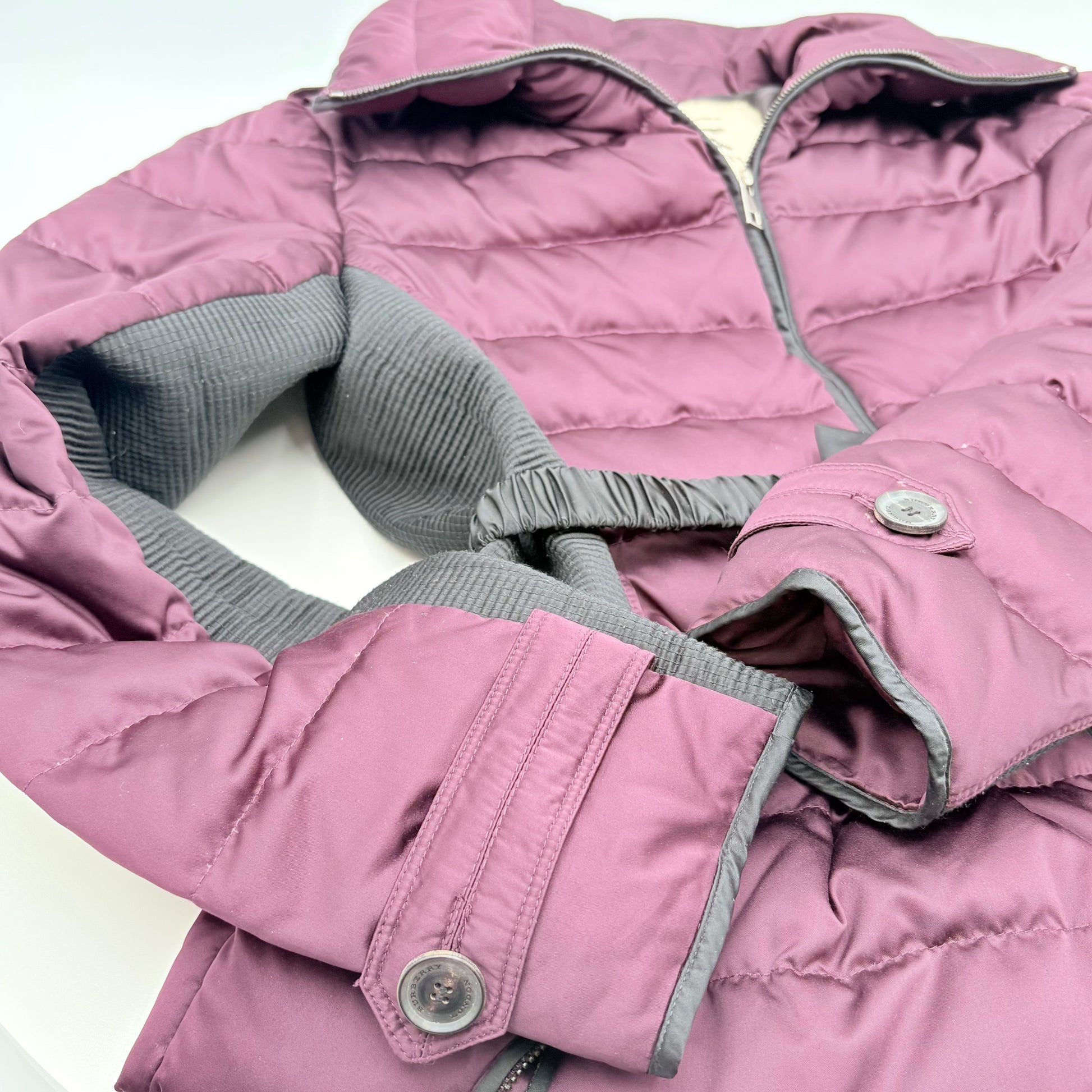 Close-up of a pink quilted jacket with gray trim on a white background