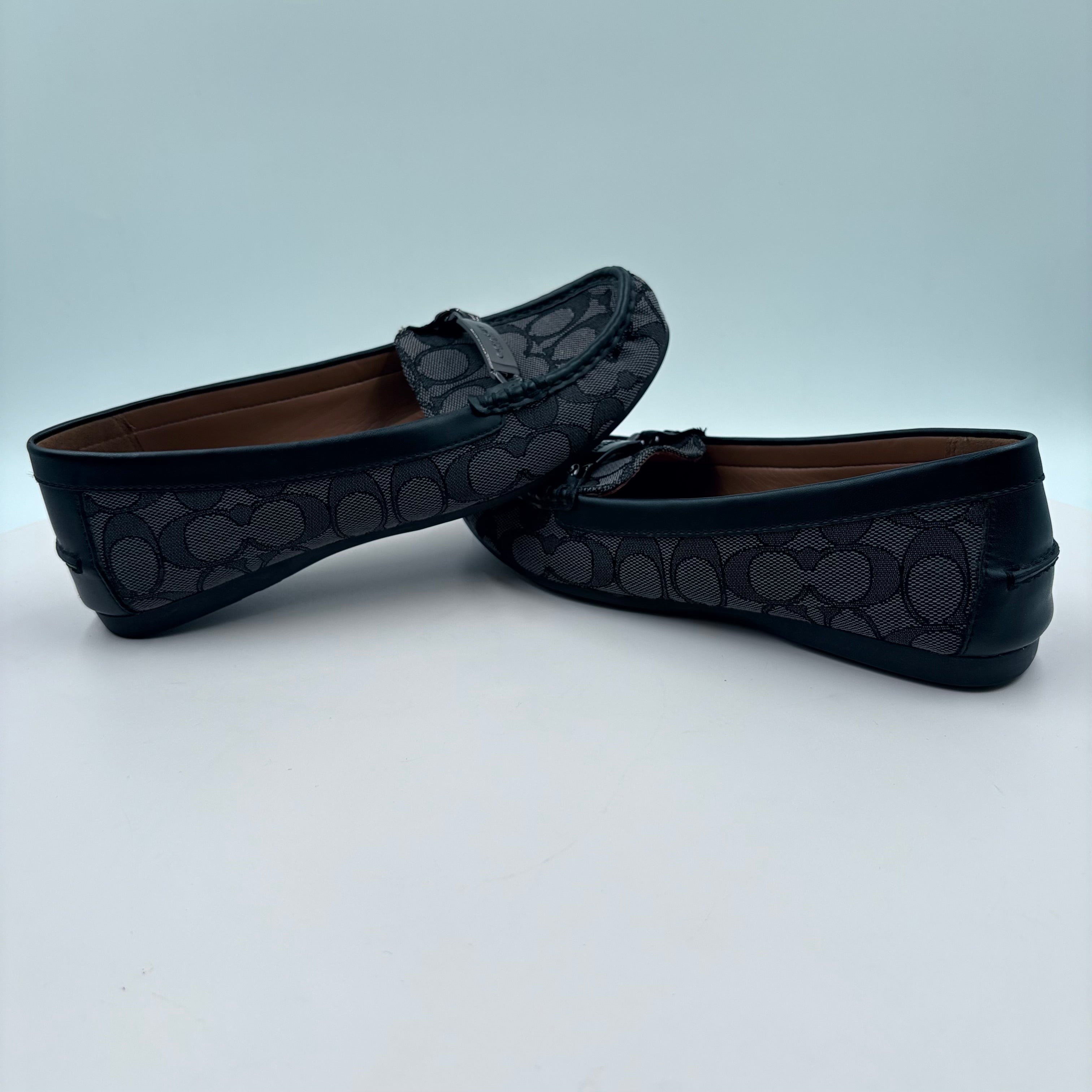Pair of black loafers with a subtle pattern on a light gray background