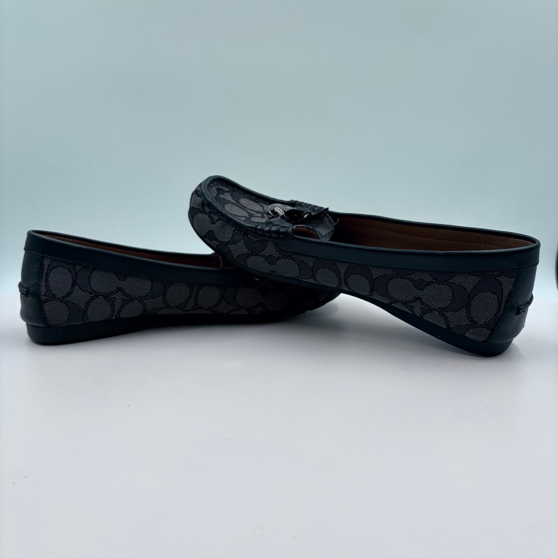 Black loafers with a pattern on a light gray background