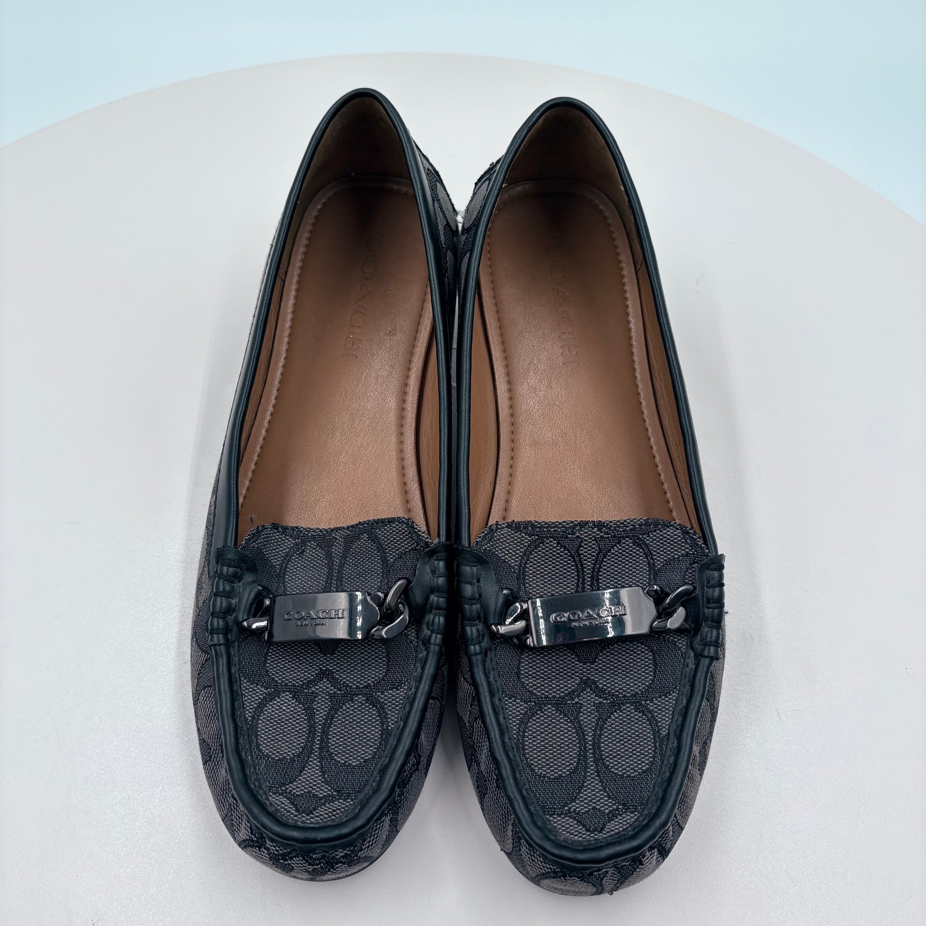 Pair of black loafers with a patterned design on a light blue background