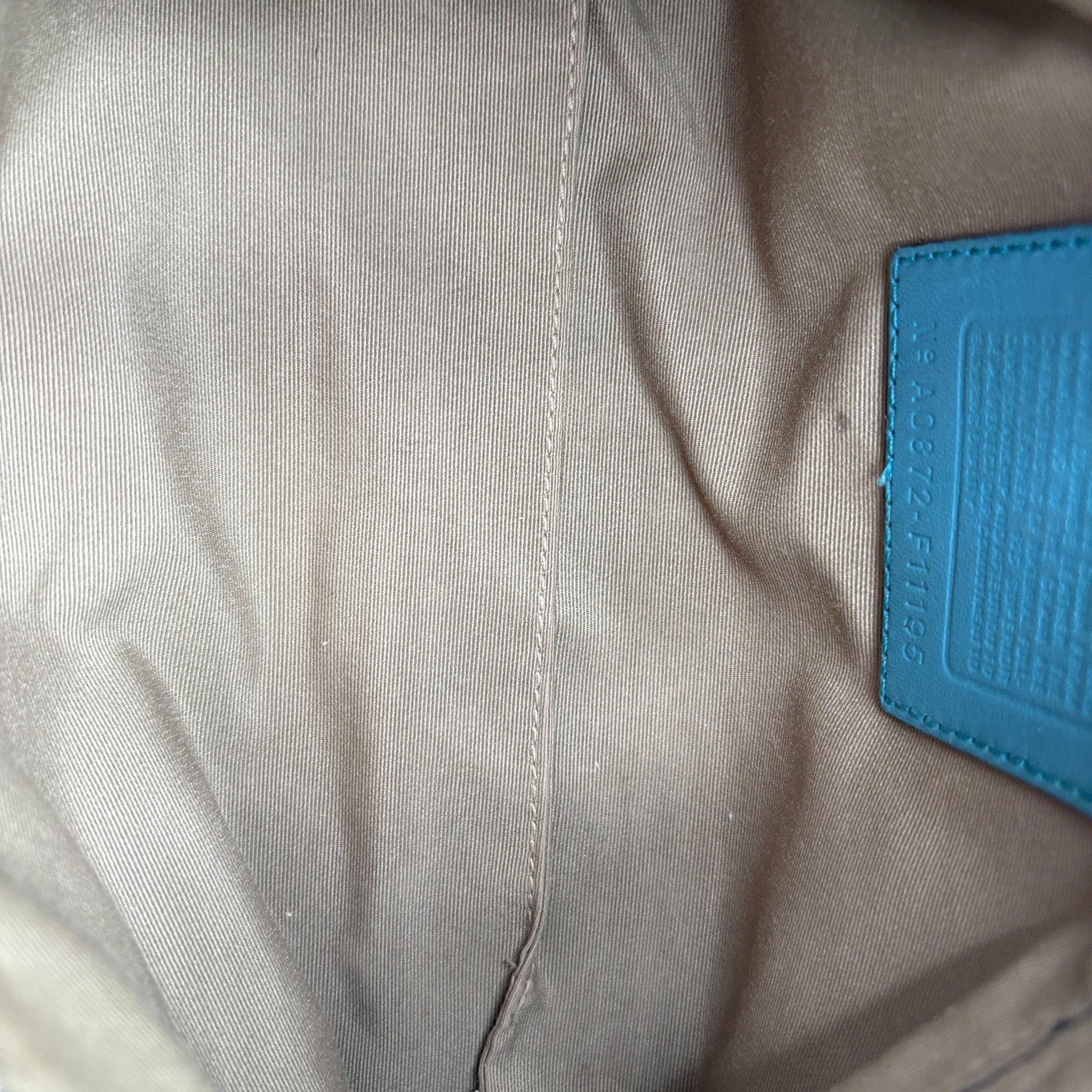 Close-up of beige fabric with a blue patch on a textured background