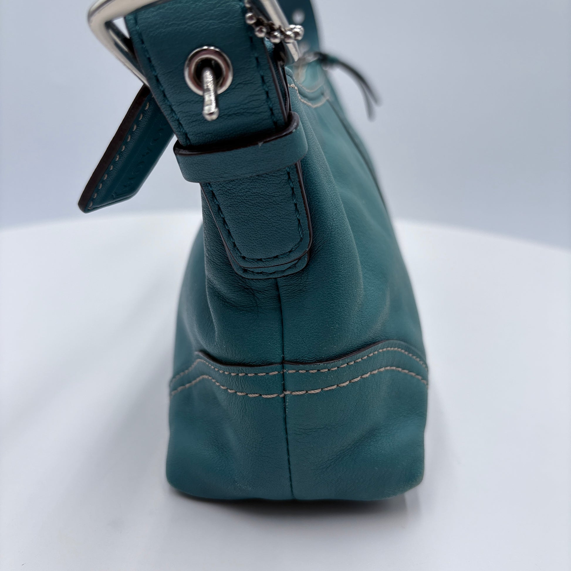 Teal handbag with a strap on a white background