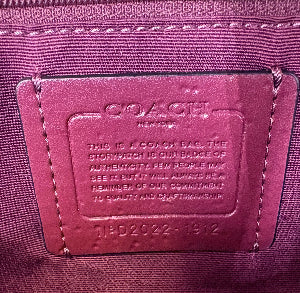 Close-up of a purple fabric tag with text and a brand logo.