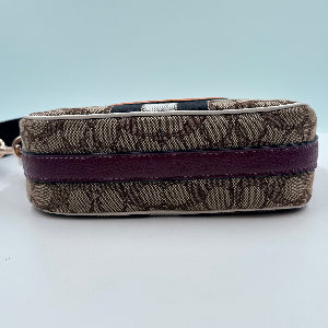 Designer handbag with brown pattern and purple strap on a light blue background