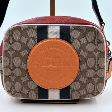 Coach handbag with signature pattern and brown leather logo on a white background