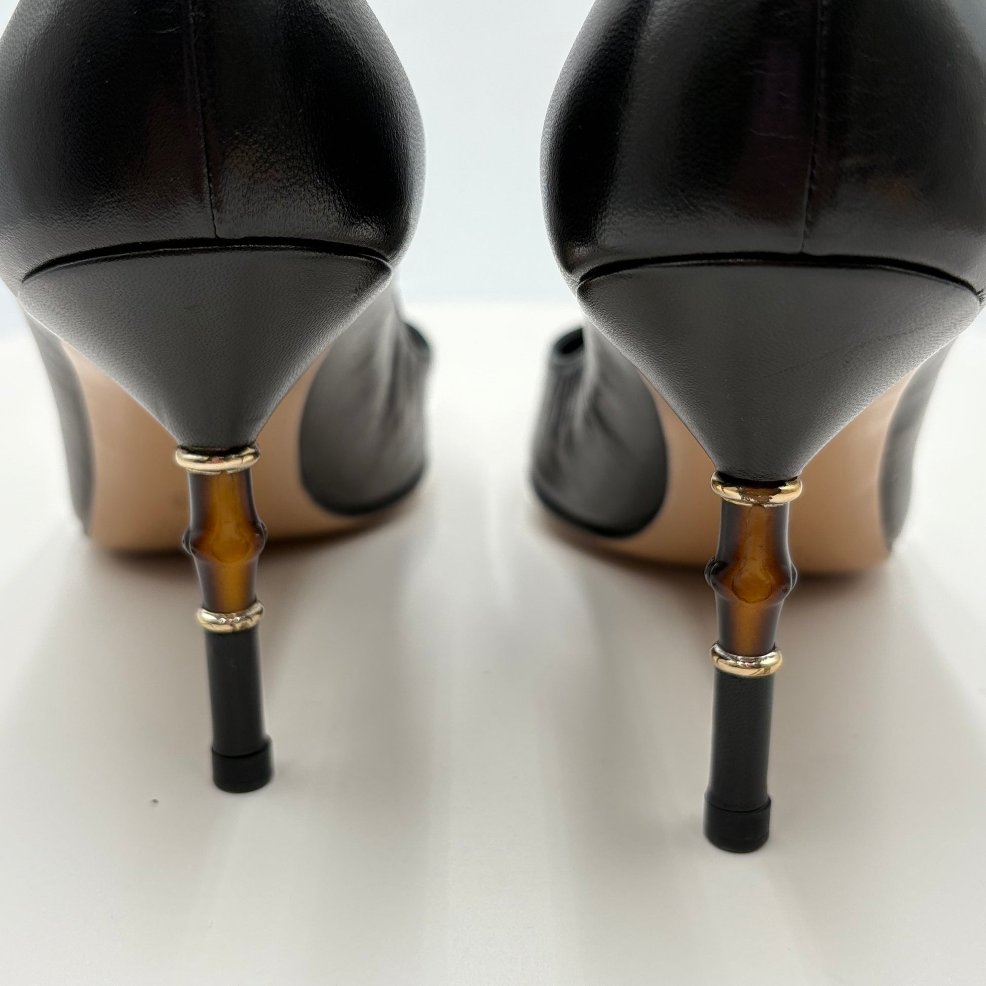 Black high-heeled shoes with unique bamboo-style heel designs on a white background