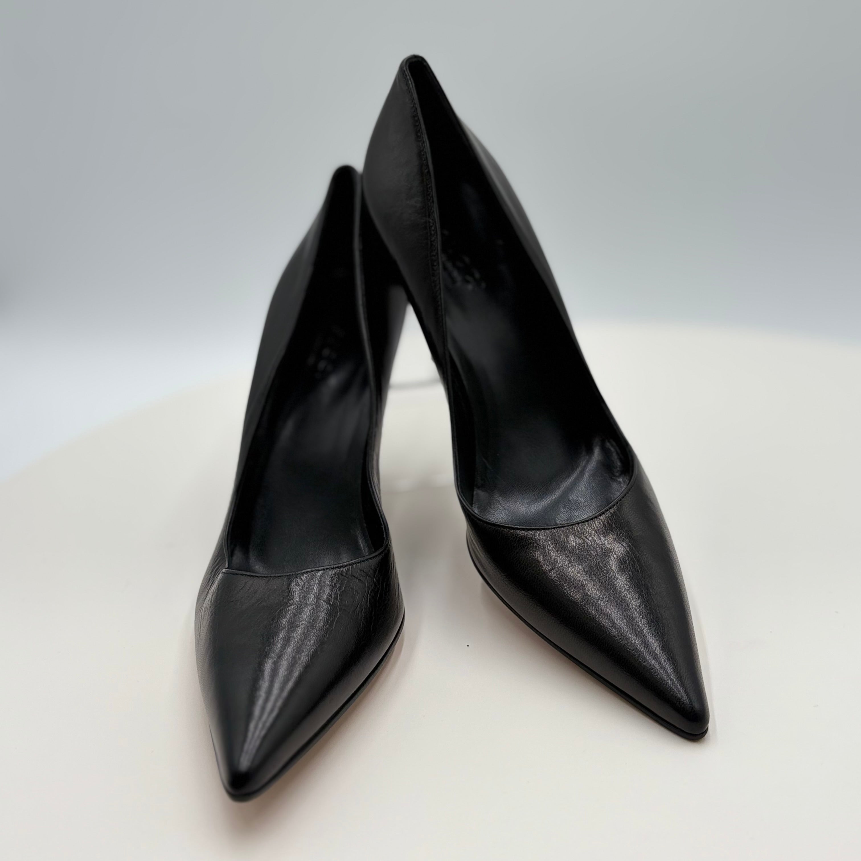 Pair of black high-heeled shoes on a white surface with a gray background