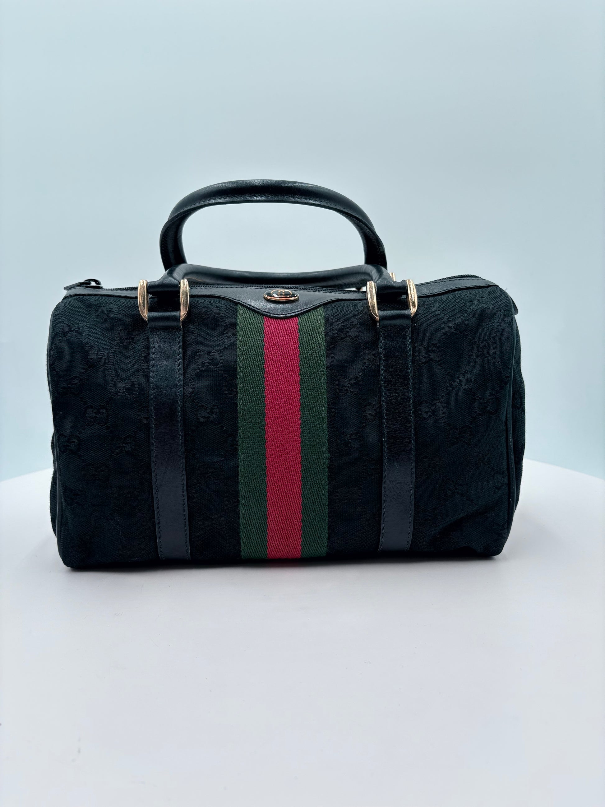 Black bag with a red and green stripe on a mannequin against a light gray background