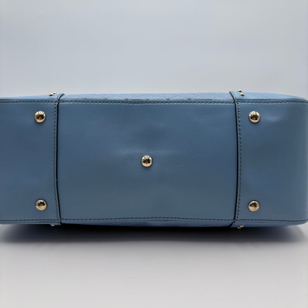 Blue handbag with gold studs on a light gray background