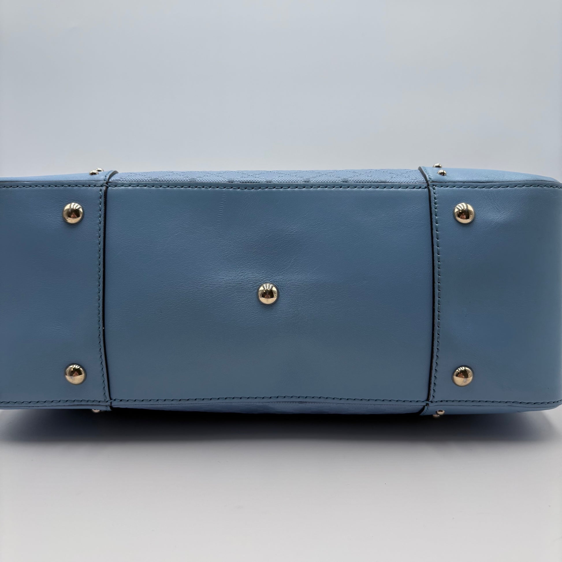 Blue handbag with gold studs on a light gray background