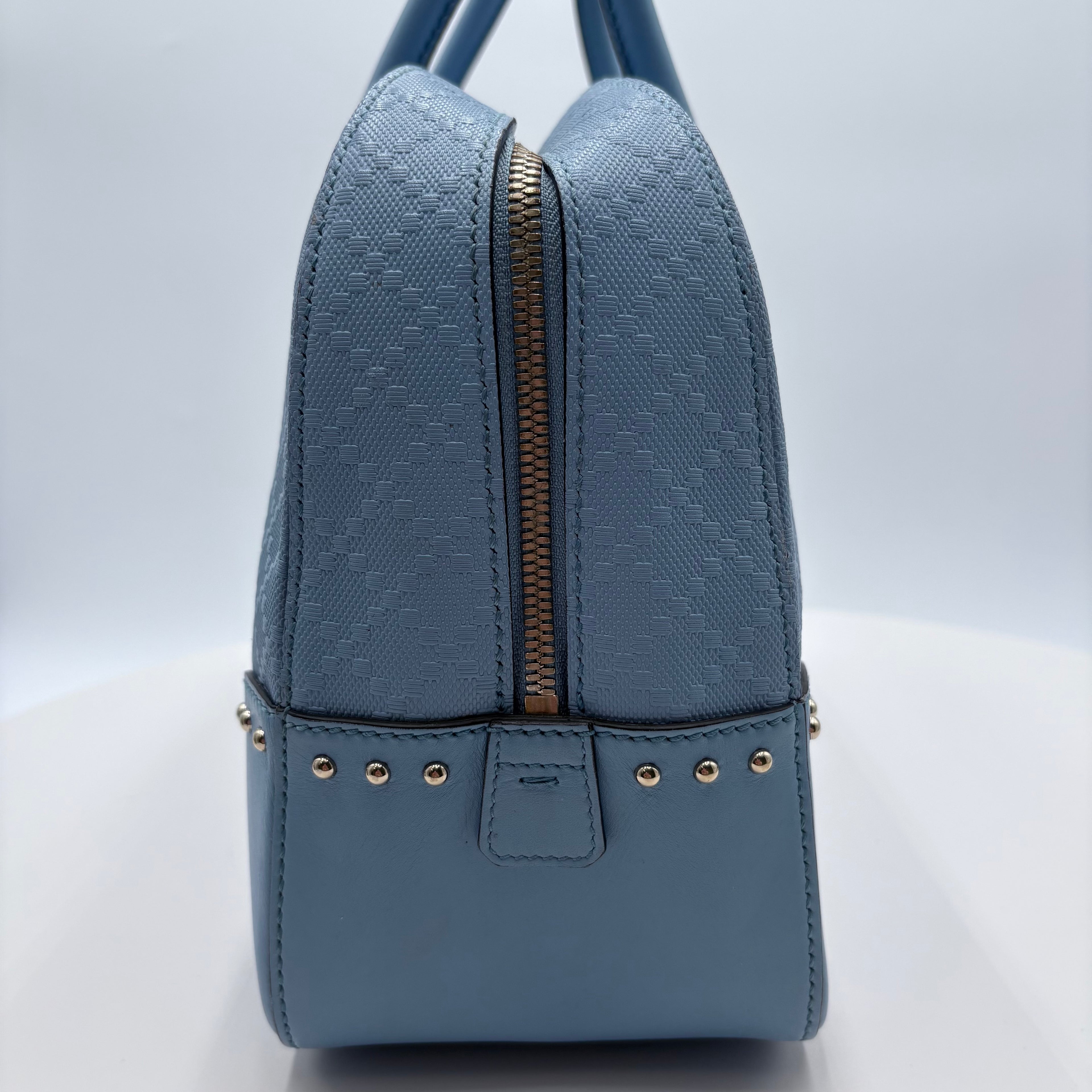 Blue textured handbag with a zipper on a light gray background