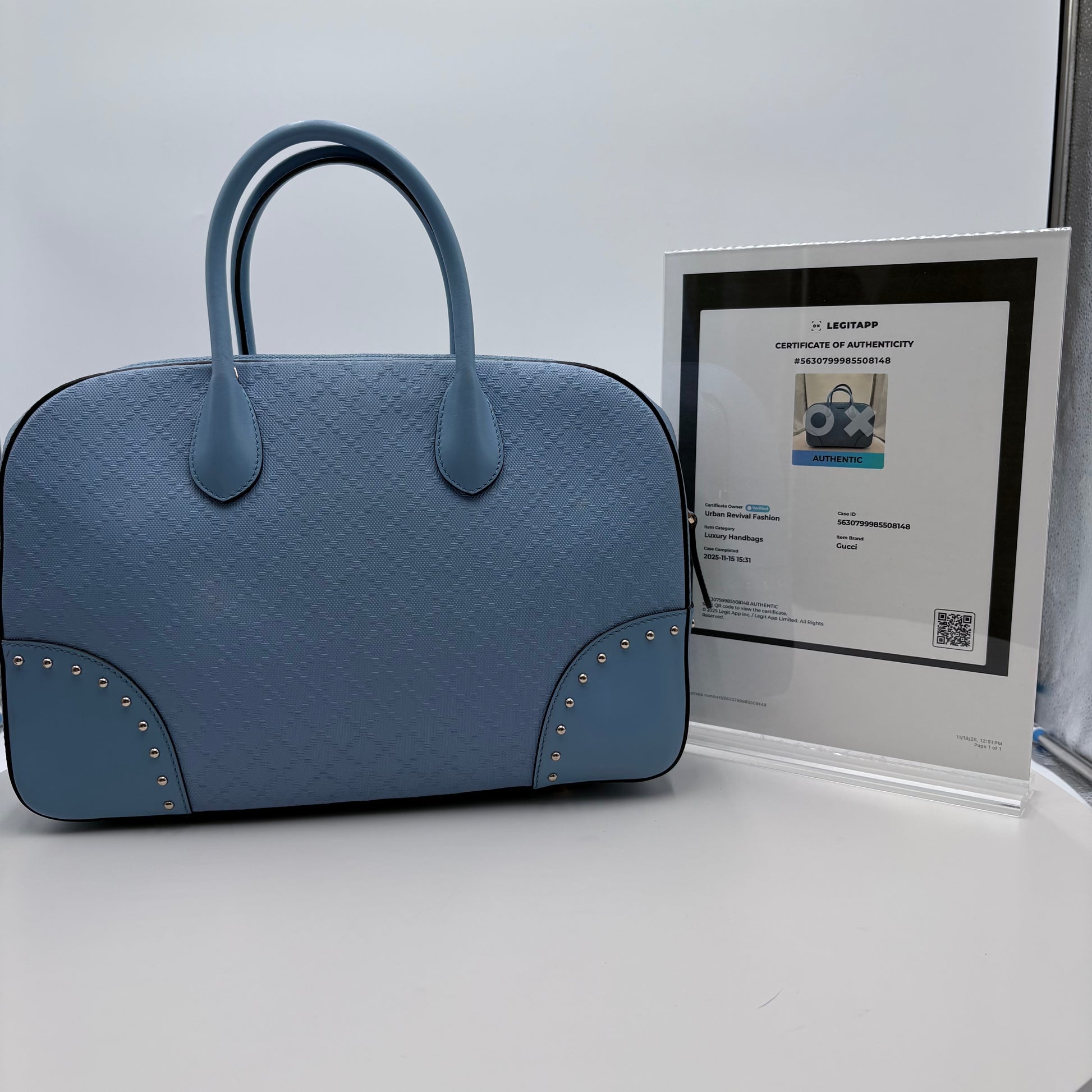 Blue textured handbag with a certificate of authenticity on a light gray background