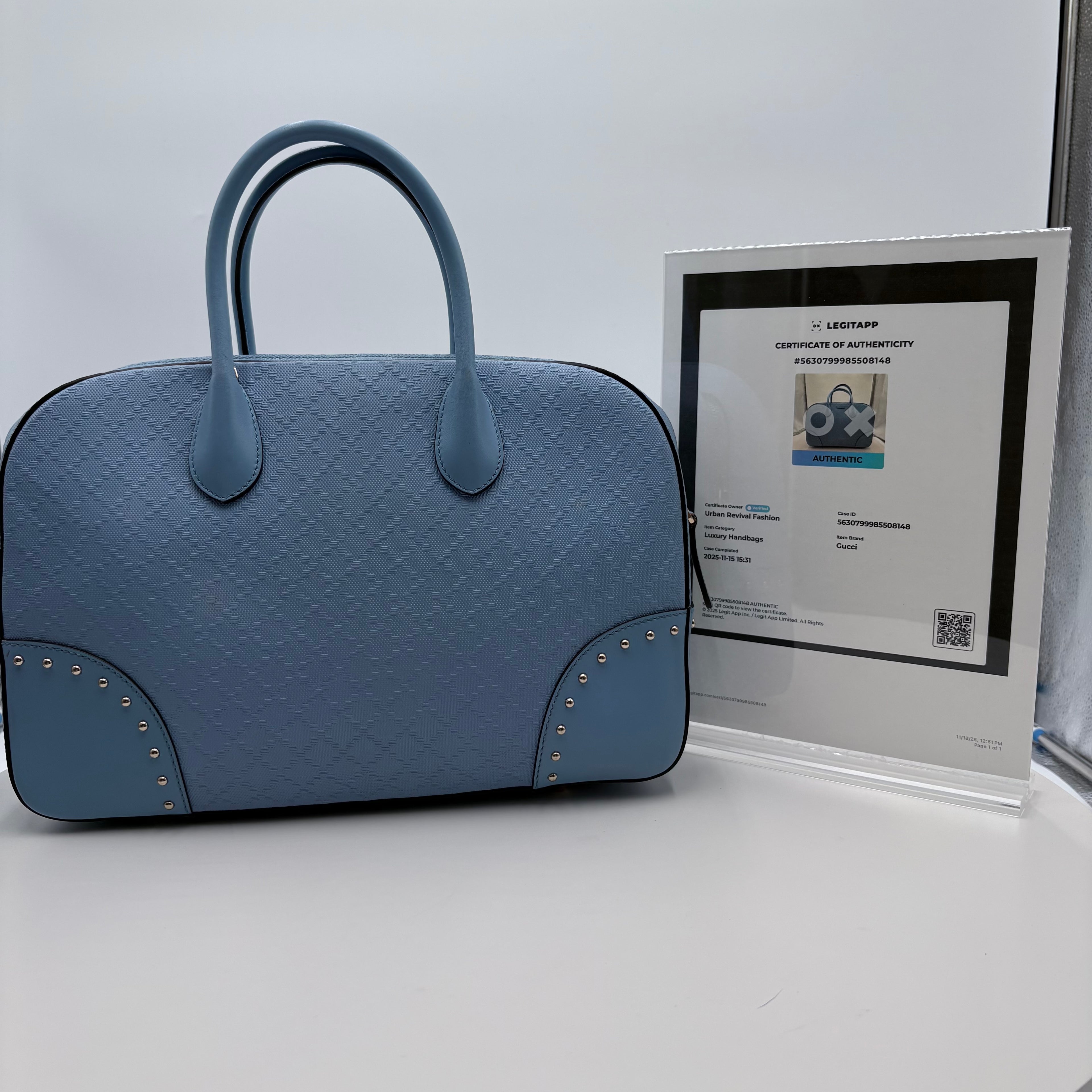 Blue textured handbag with a certificate of authenticity on a light gray background