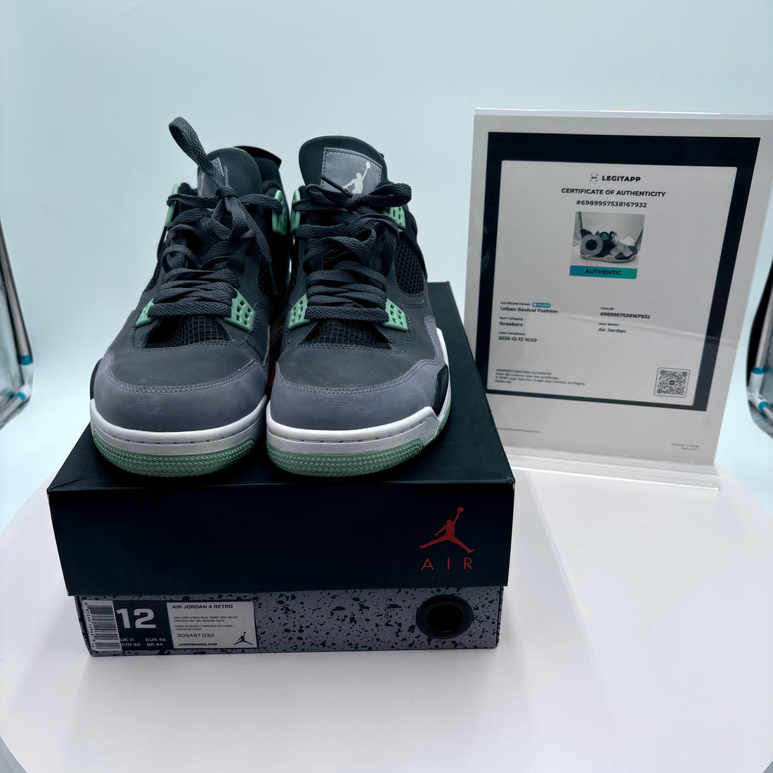 Pair of black and gray sneakers on a black box with a Jordan logo, next to a certificate of authenticity.