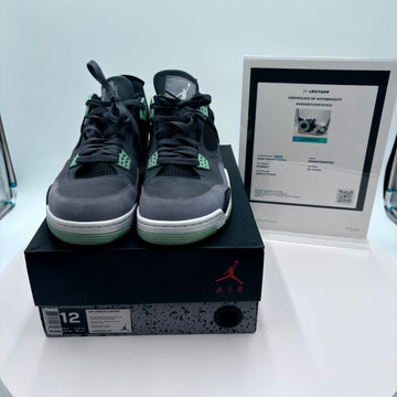 Pair of black and gray sneakers on a black box with a Jordan logo, next to a certificate of authenticity.