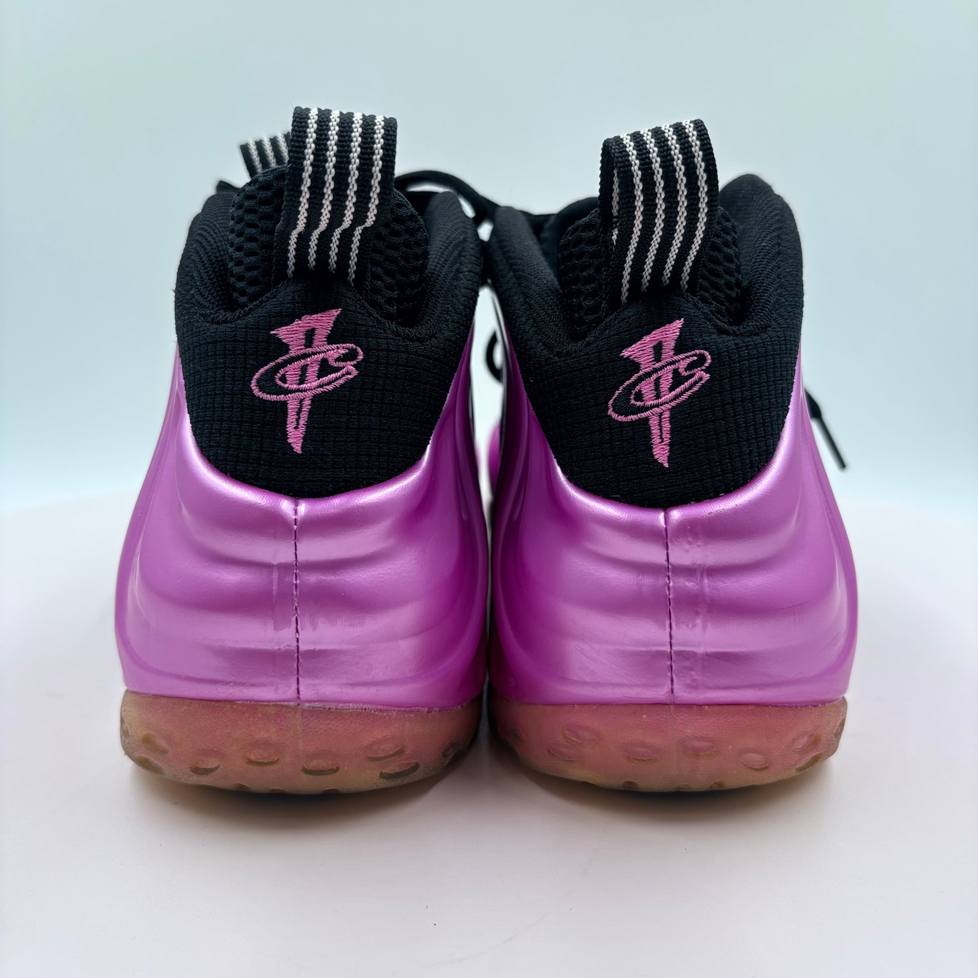 Purple sneakers with black swoosh logo on a light gray background