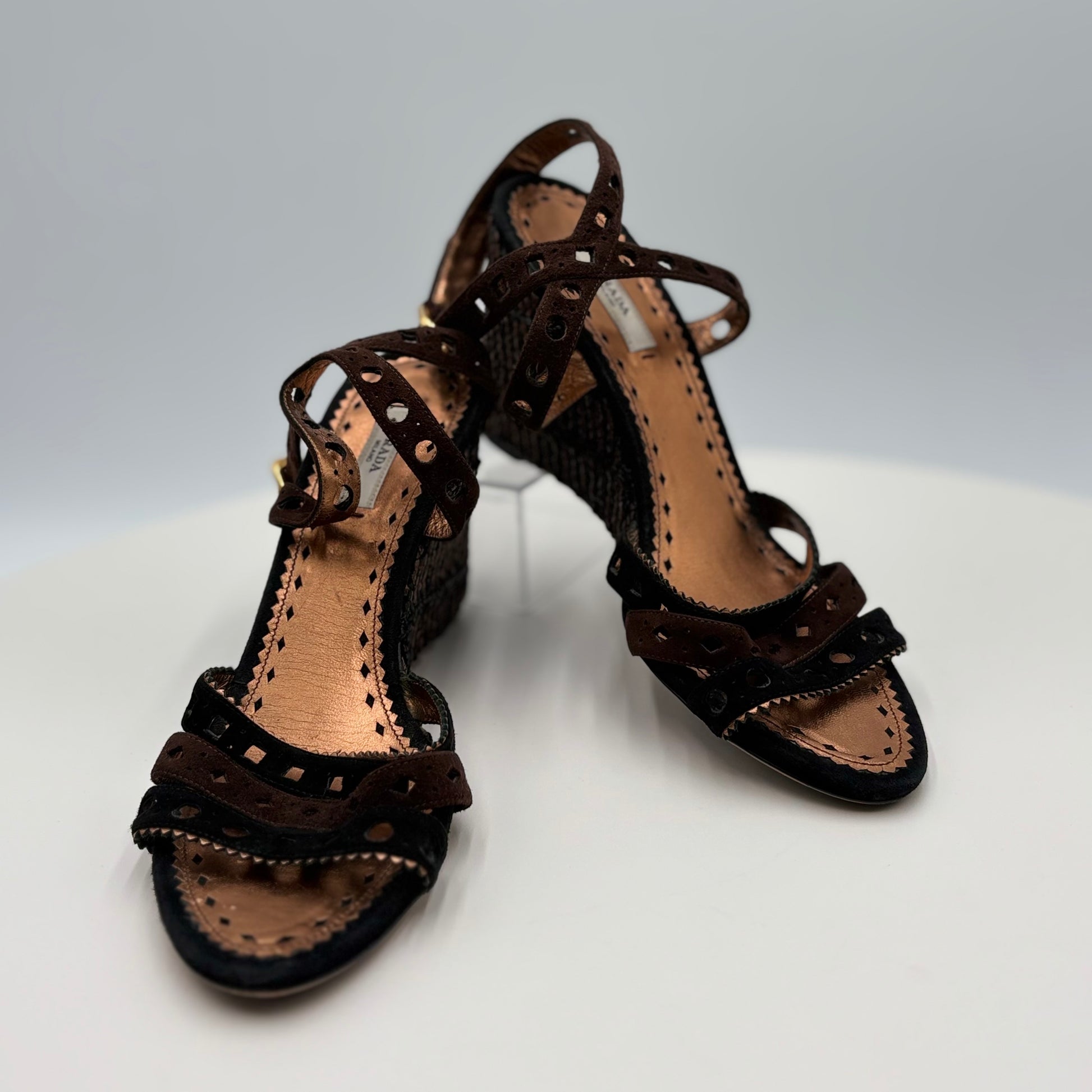 Pair of brown strappy sandals on a white surface with a gray background