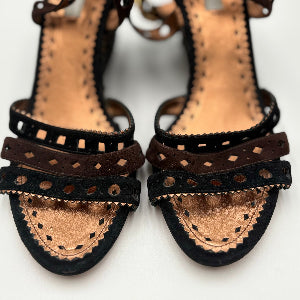 Pair of black sandals with detailed straps on a white background