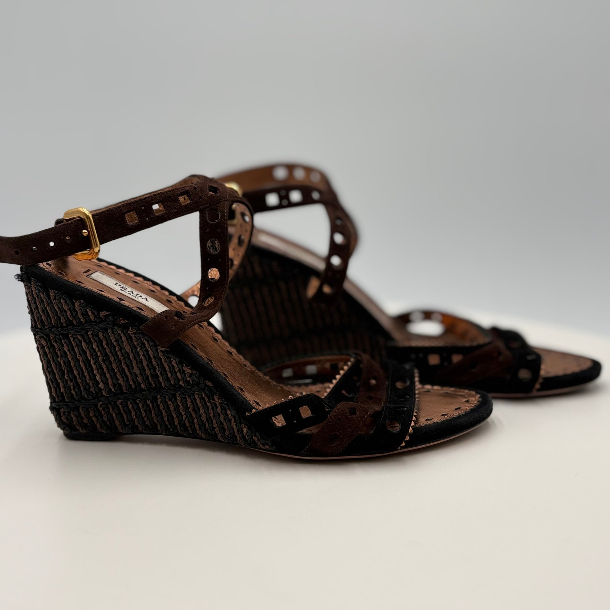Brown wedge sandals with decorative straps on a light gray background