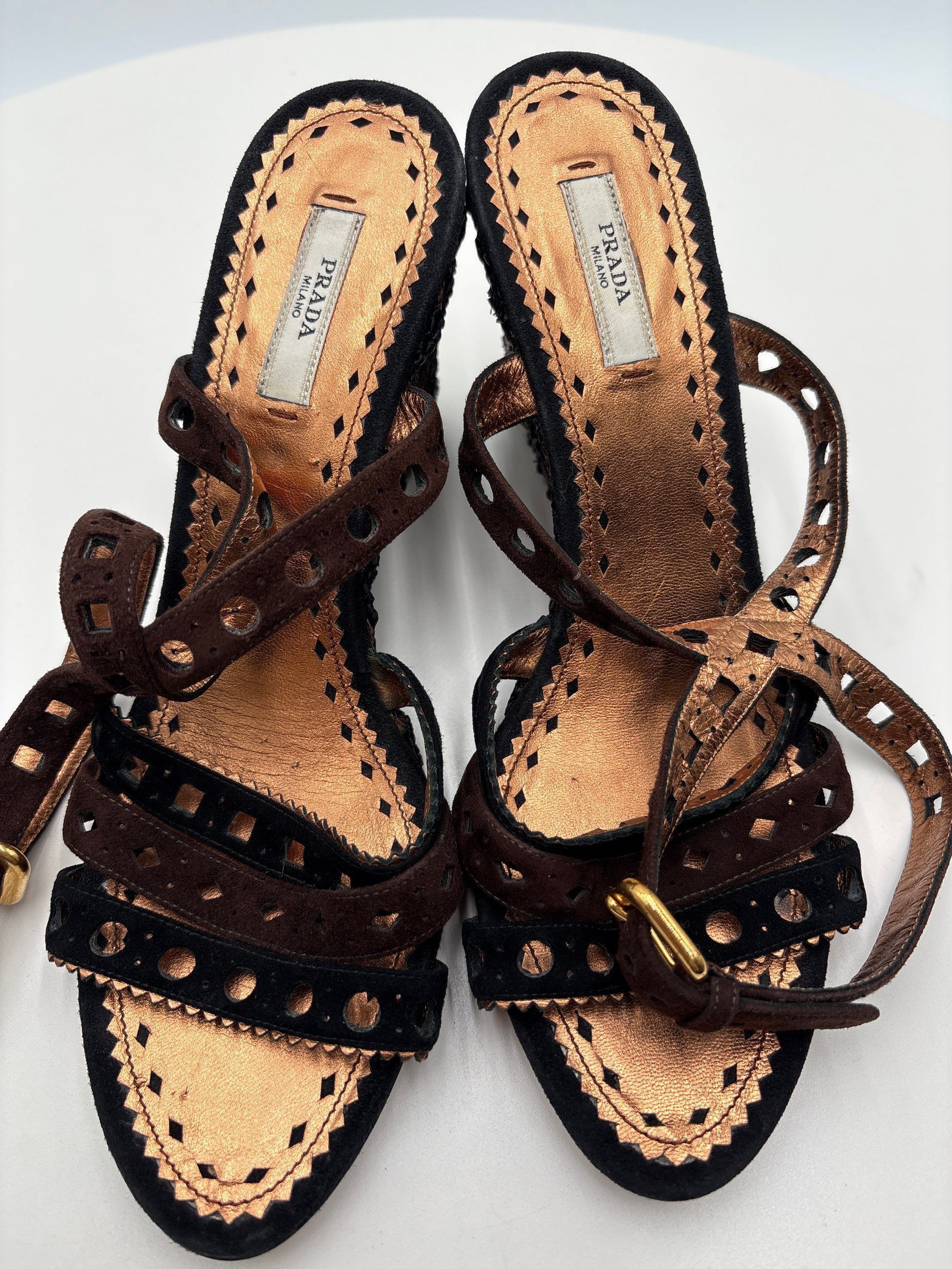 Pair of Prada sandals with decorative straps on a white background