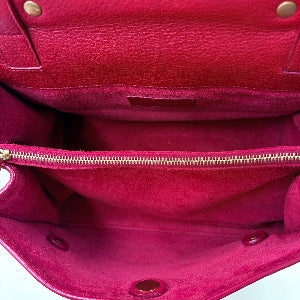 Close-up of a red leather handbag with gold zipper and hardware.
