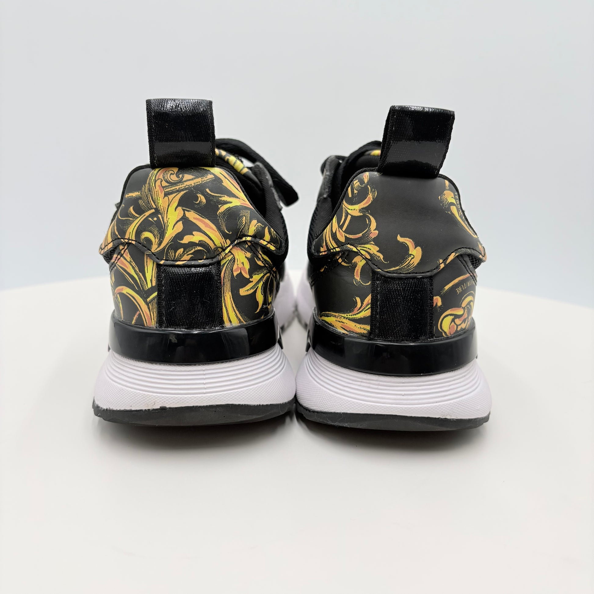 Black and gold patterned sneakers on a white background