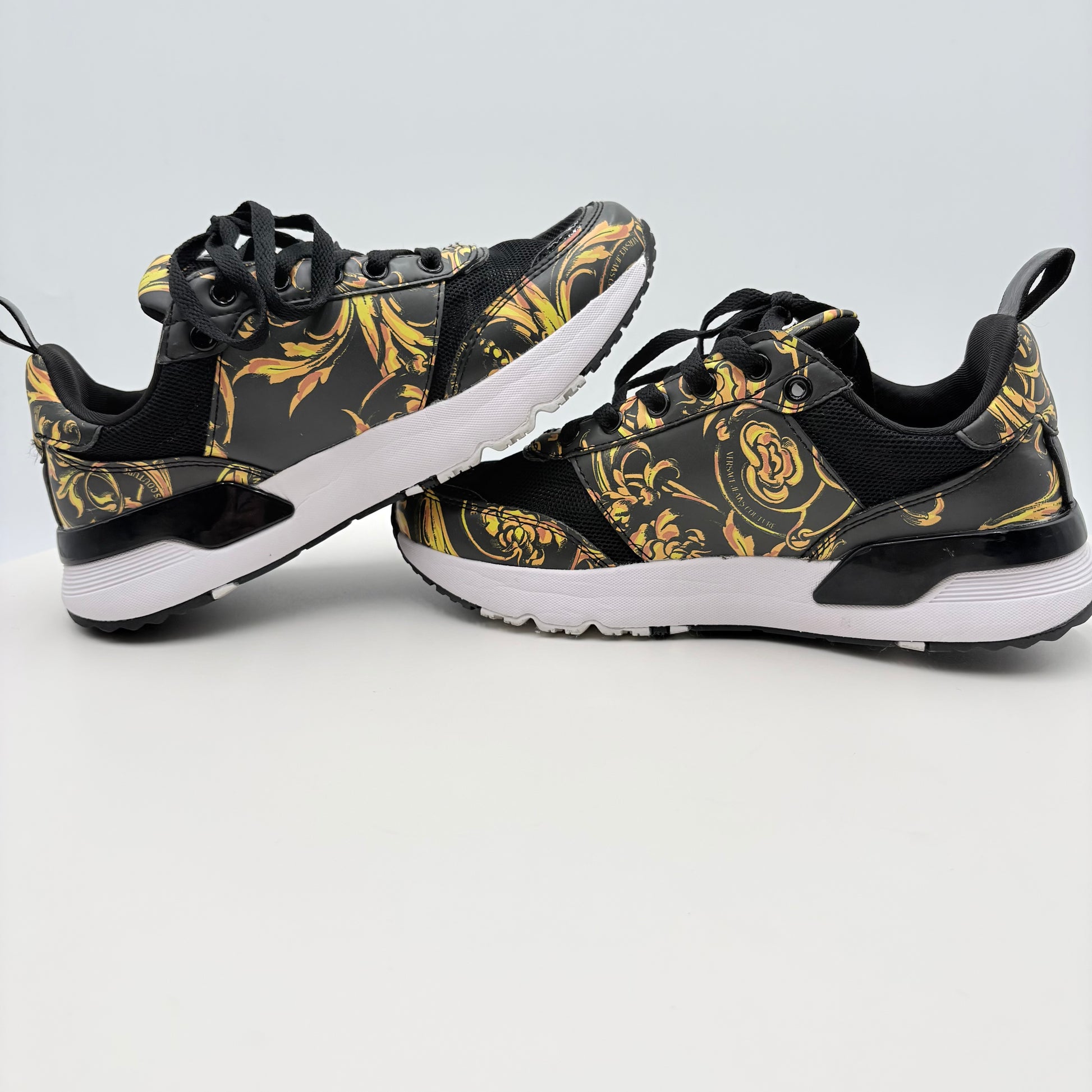 Black and gold patterned sneakers on a light gray background
