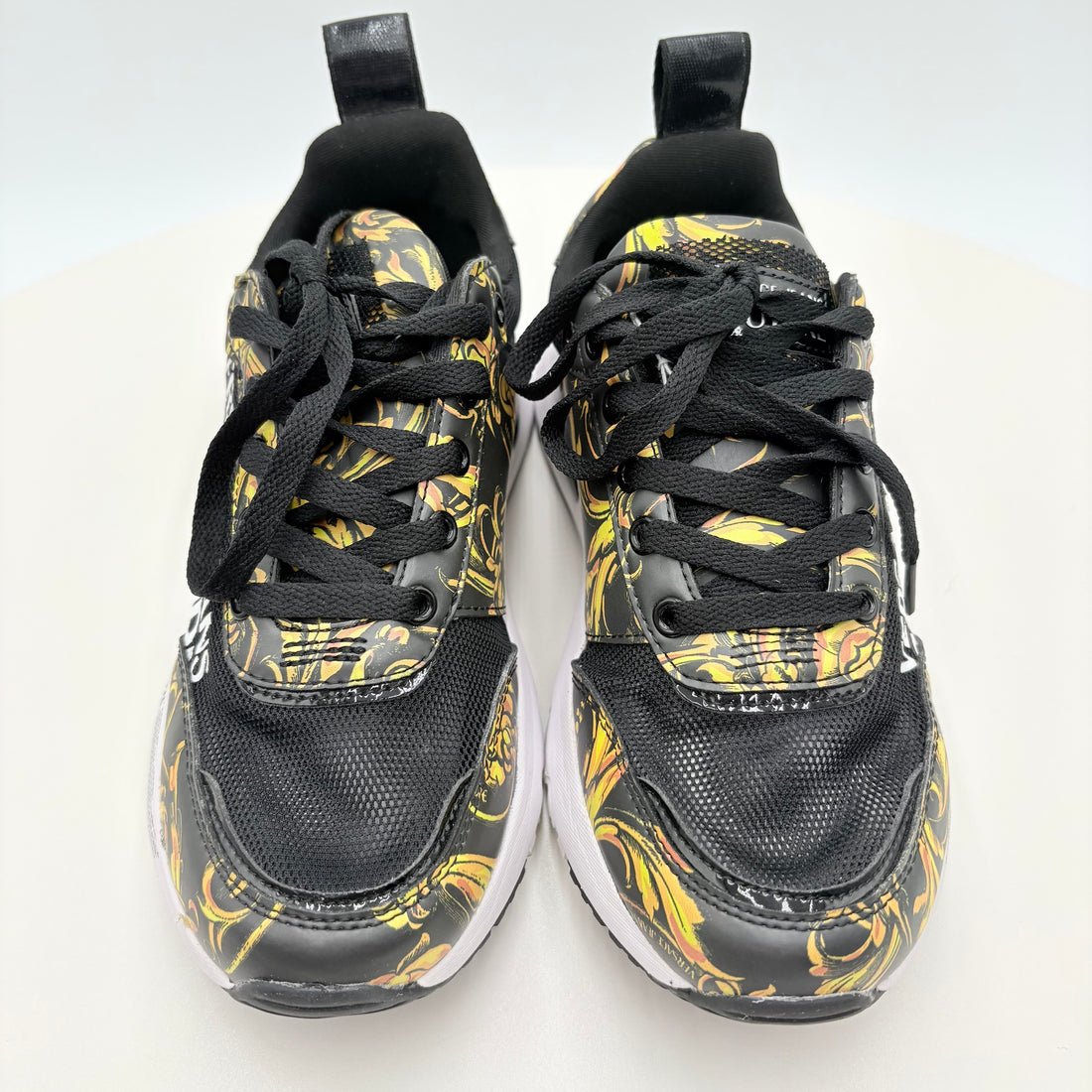 Black and yellow patterned sneakers with a certificate of authenticity on a white background