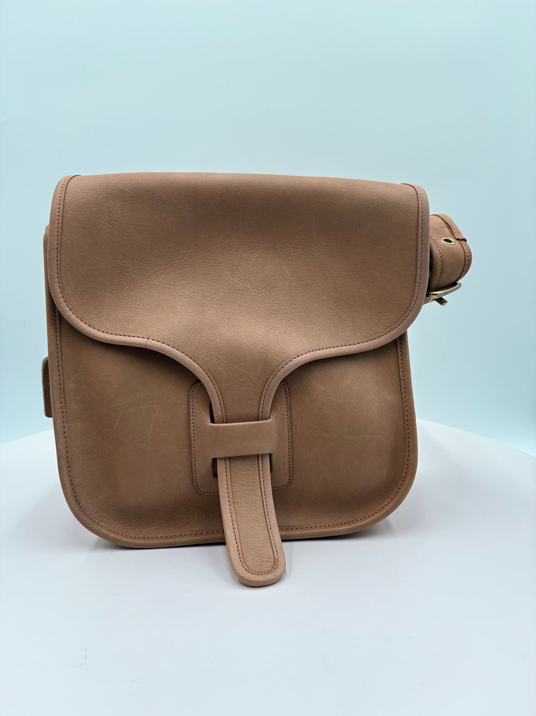 Brown leather saddle bag on a light blue background