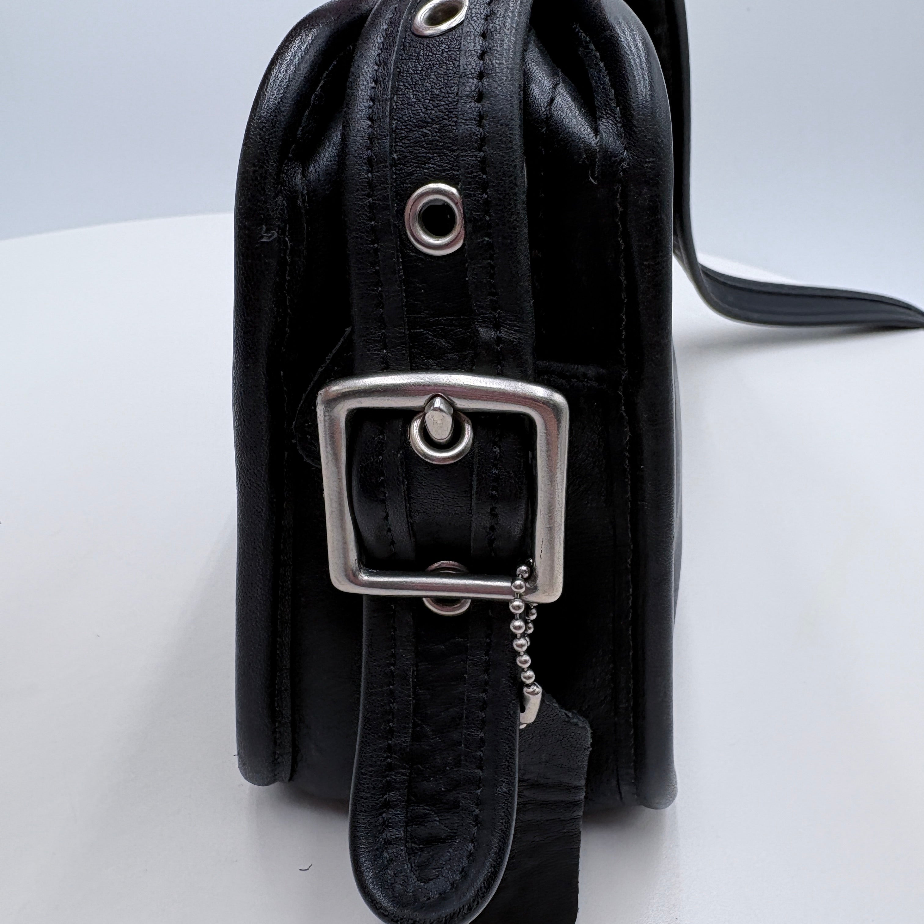 Black leather handbag with silver buckle on a white background