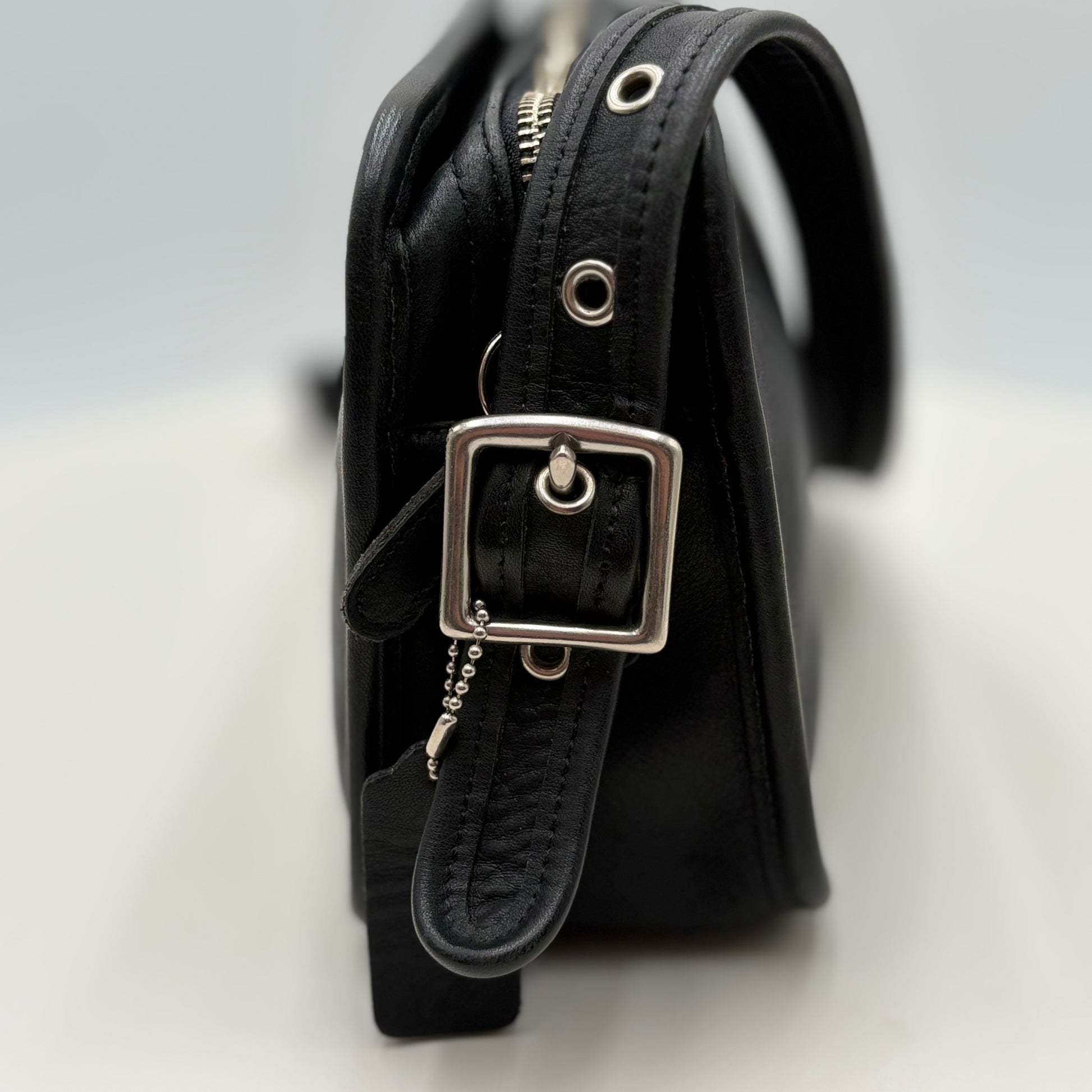Black leather belt with silver buckle on a light gray background