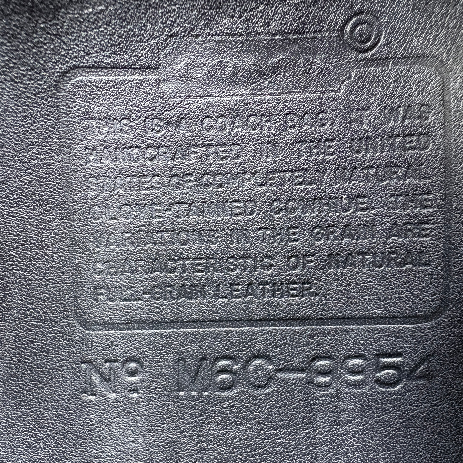 Textured leather surface with embossed branding and product details.