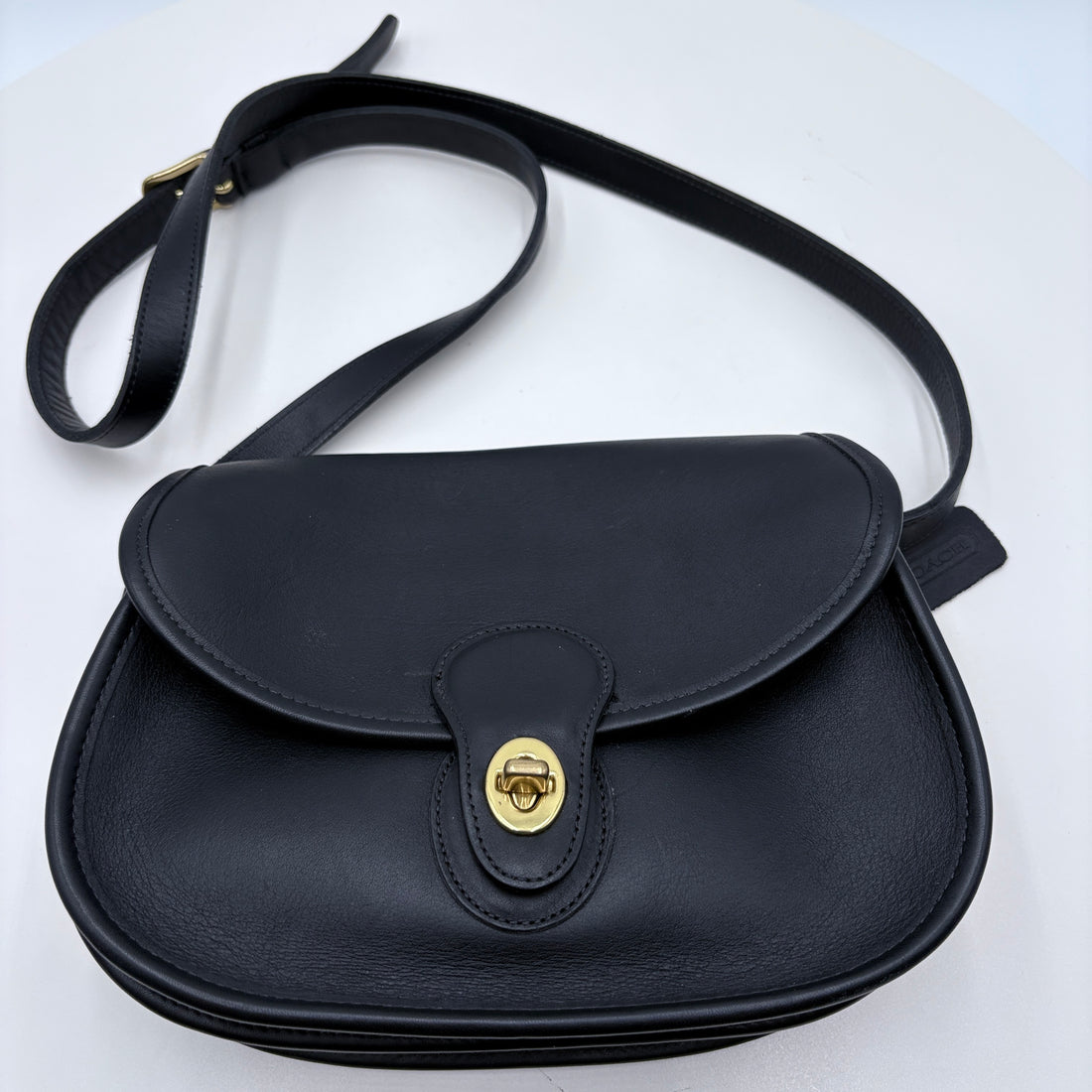 Black leather handbag with a gold clasp on a white background