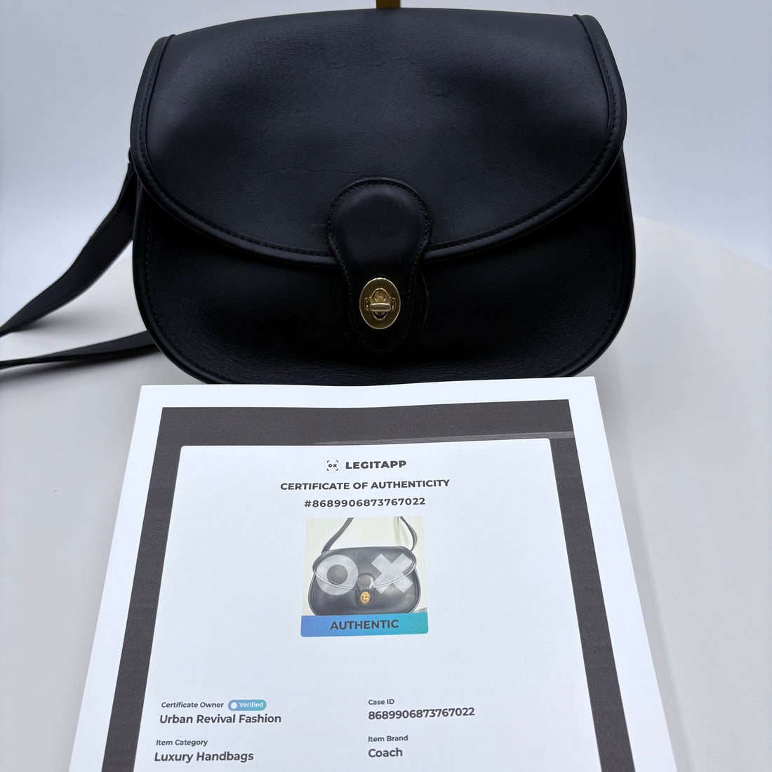 Black leather handbag with a gold clasp on a white background