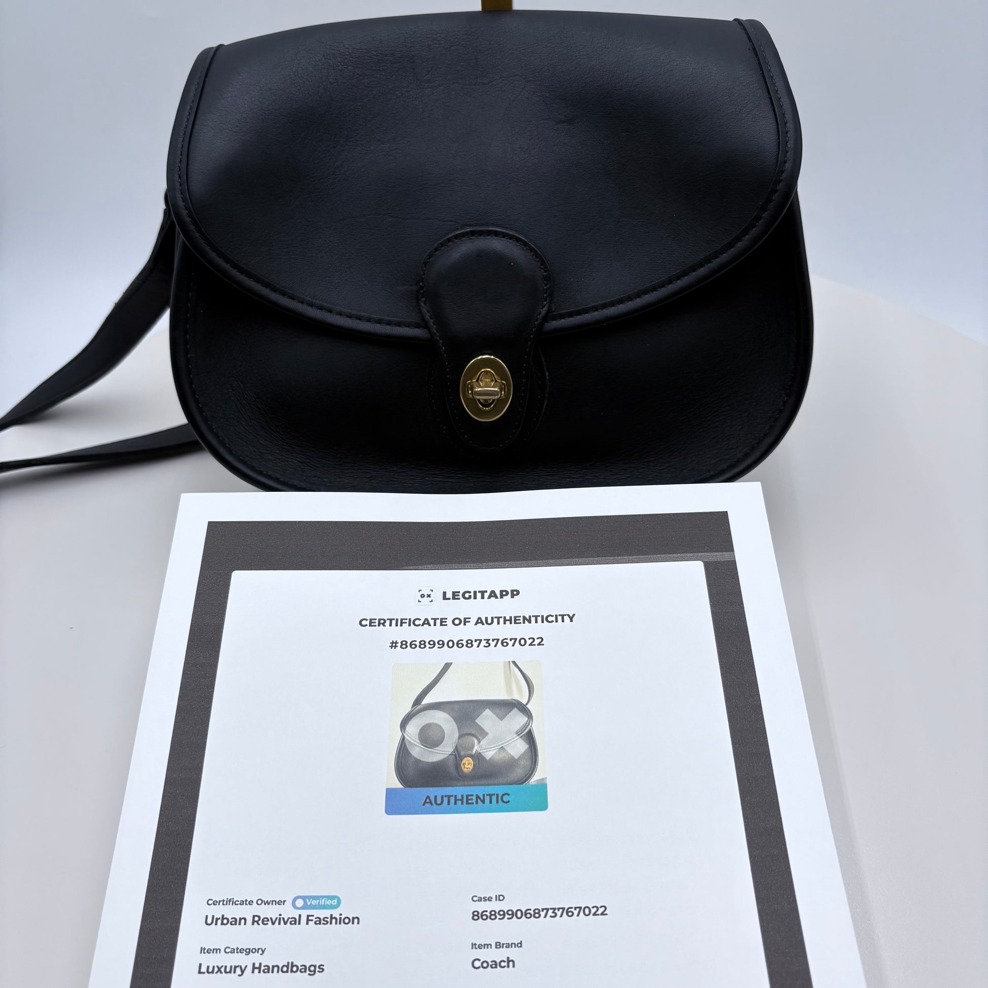 Black handbag with a certificate of authenticity on a light gray background