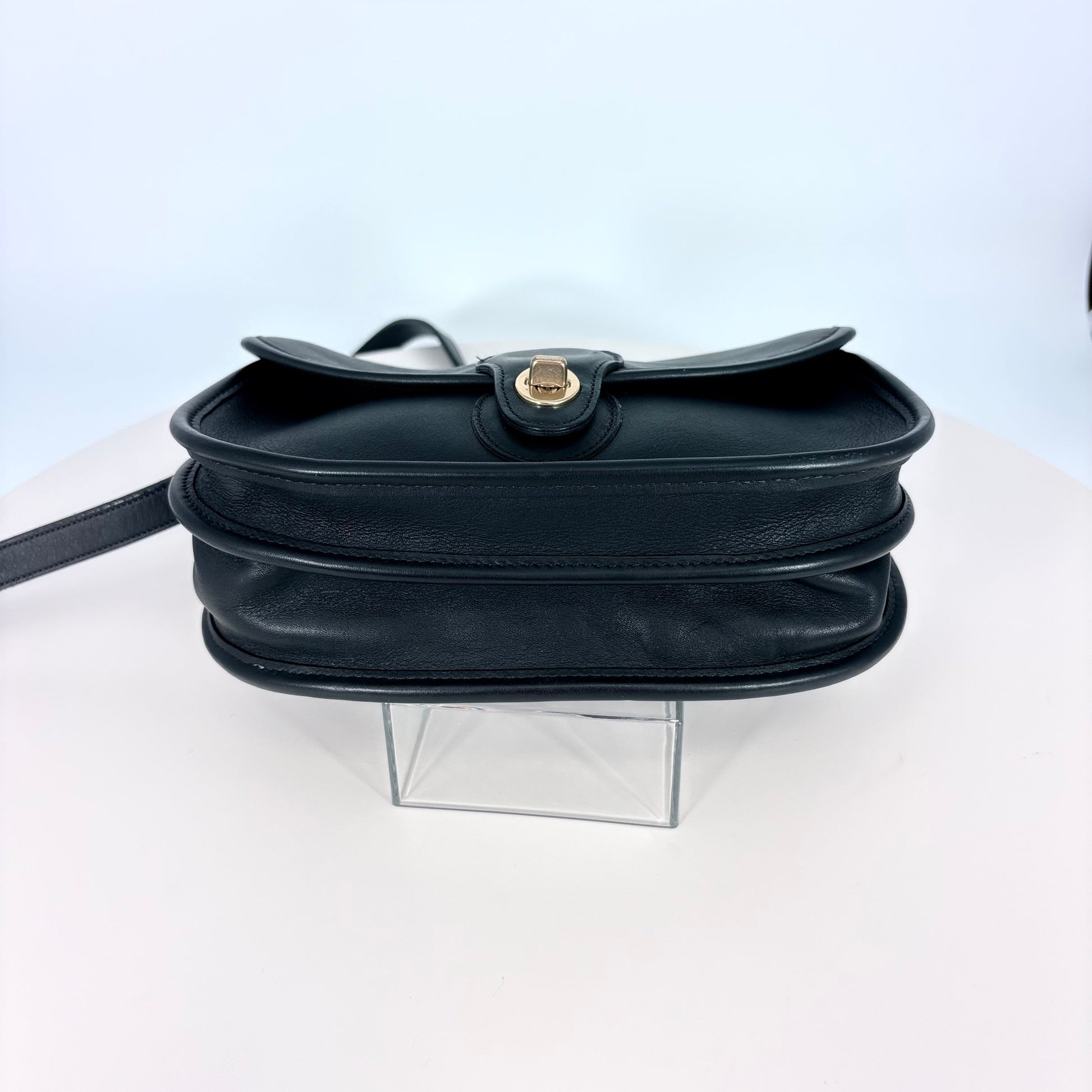 Black handbag on a clear stand against a white background