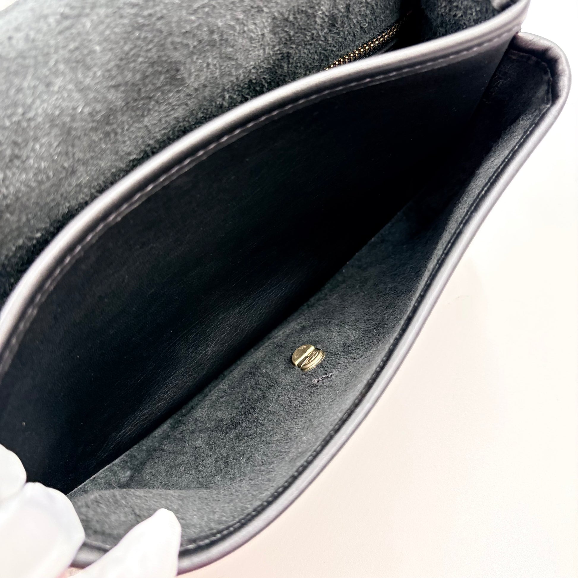Close-up of a handbag's interior with a gold clasp on a neutral background