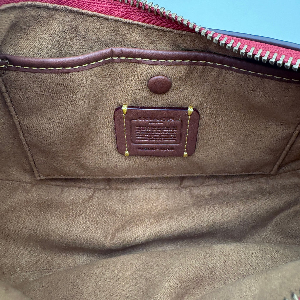 Close-up of a brown leather bag with a visible brand label on a light blue background