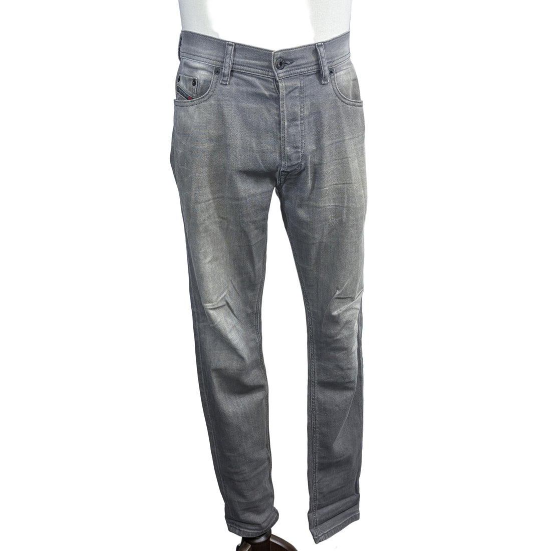 Gray jeans on a mannequin against a plain background