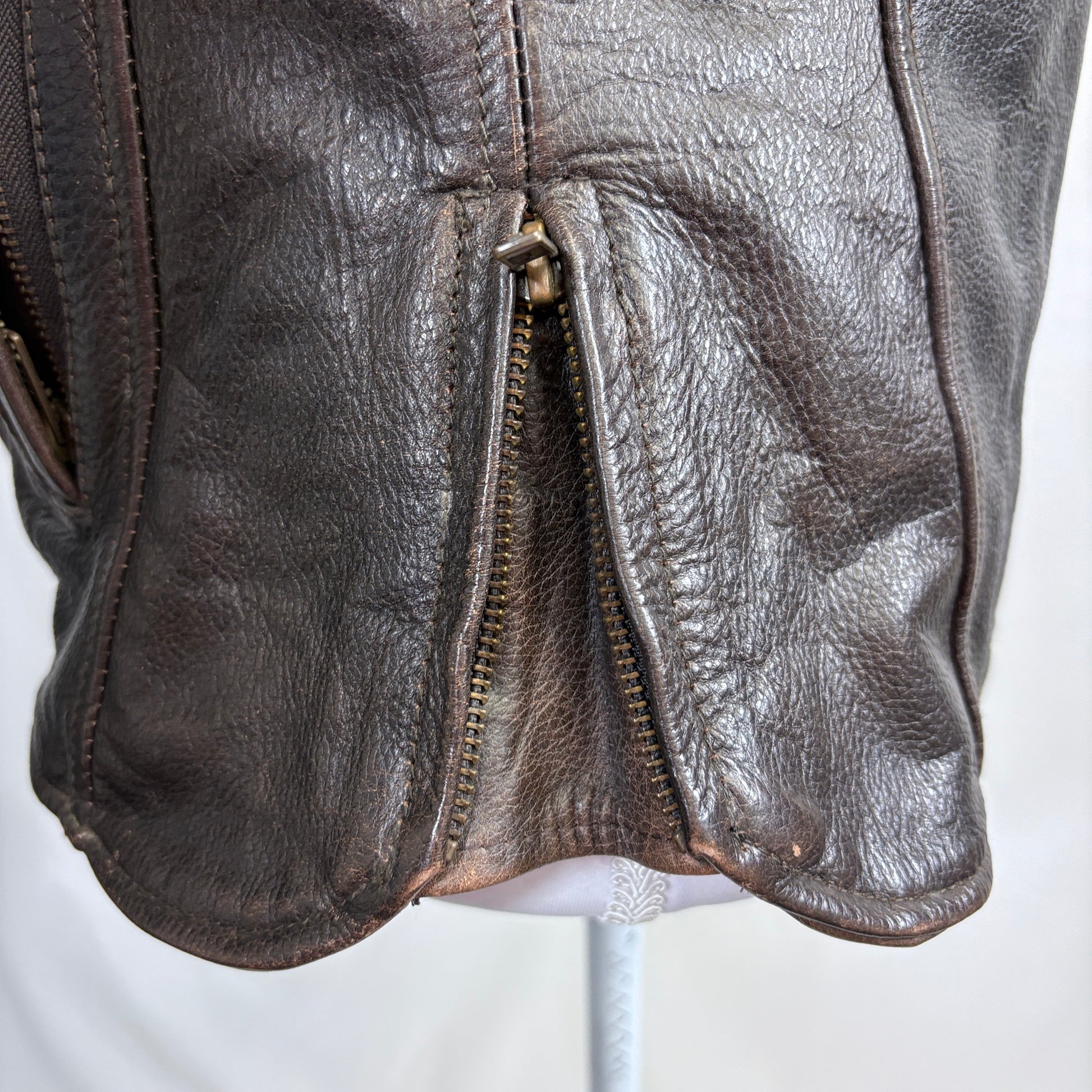 Close-up of a brown leather jacket with a zipper on a white background