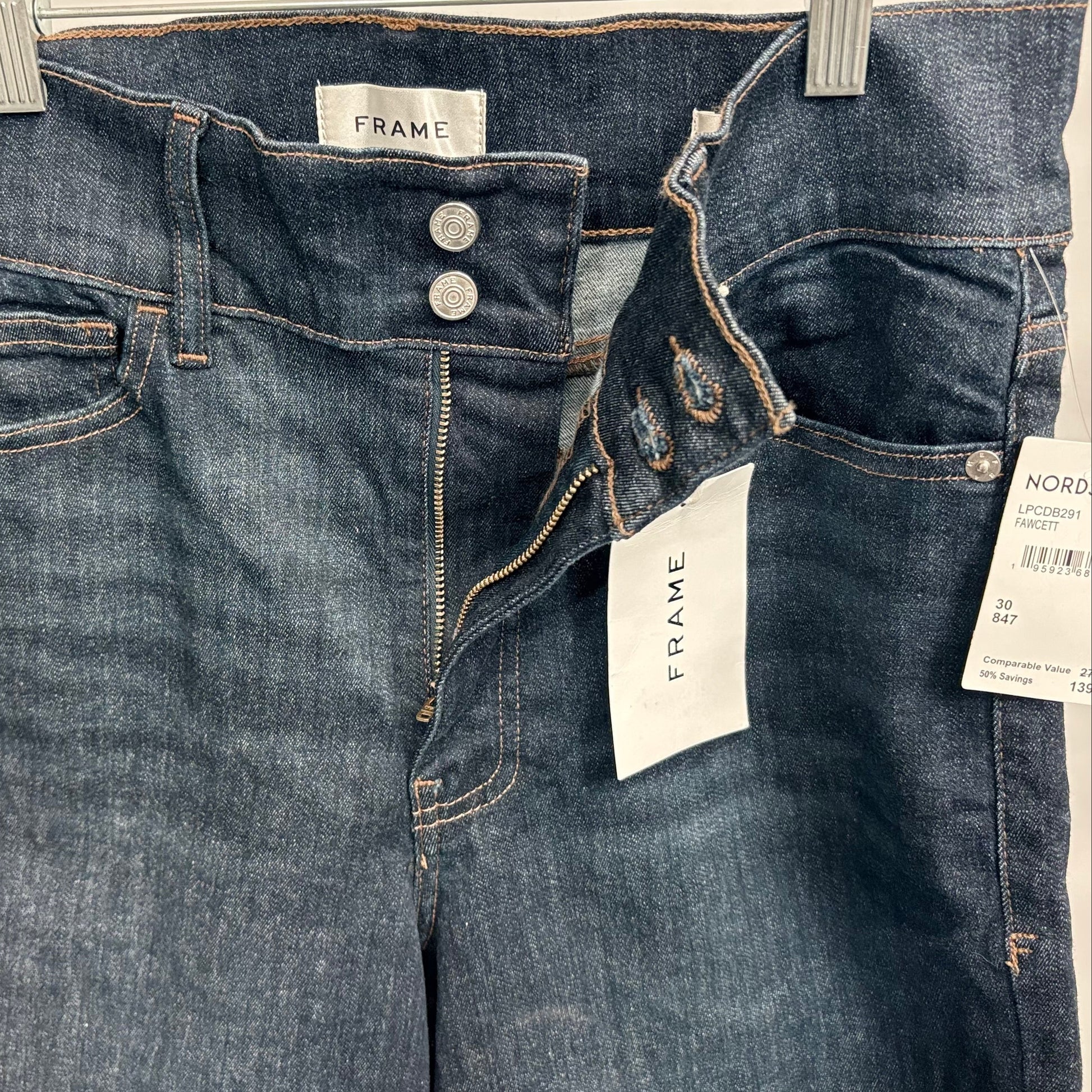 Pair of blue jeans with Frame and Nordstrom tags on a white background