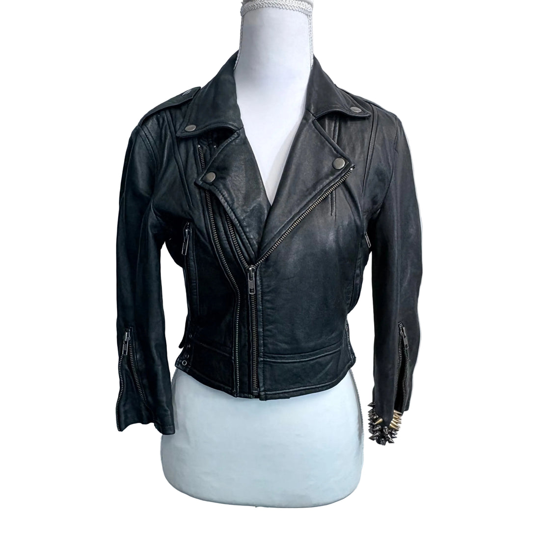 Black leather jacket on a mannequin against a plain background